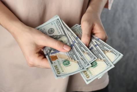 Alimony. Woman with dollar banknotes on grey background