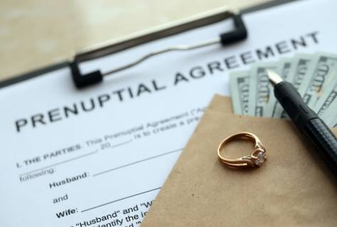Prenuptial agreement and wedding ring on table